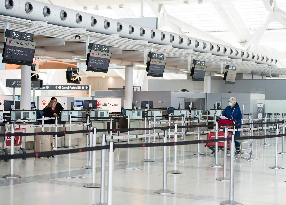 A lone lady walks in an empty Air Canada line at Pearson International Airport in Toronto on Wednesday, April 8, 2020. Health officials and the government have asked that people stay inside to help curb the spread of the coronavirus also known as COVID-19. THE CANADIAN PRESS/Nathan Denette.