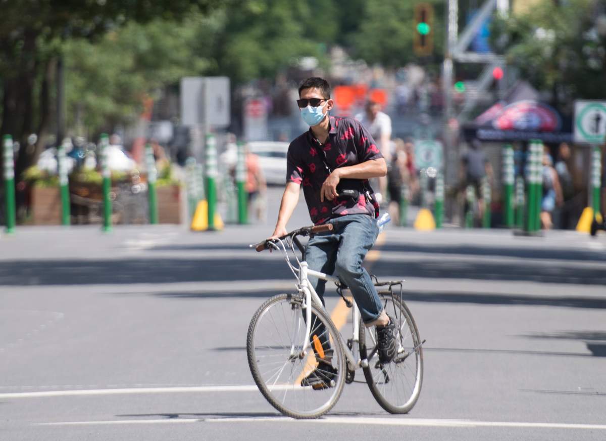 A man wears a face mask as he cycles on a street on Canada Day in Montreal, Wednesday, July 1, 2020, as the COVID-19 pandemic continues in Canada and around the world. 