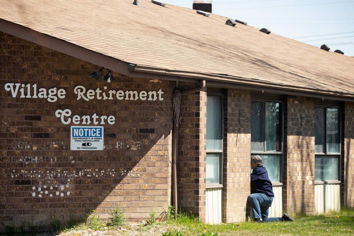 A woman tries to speak to her mother, through a window at Orchard Villa Care home, in Pickering, Ont. on Saturday, April 25, 2020.