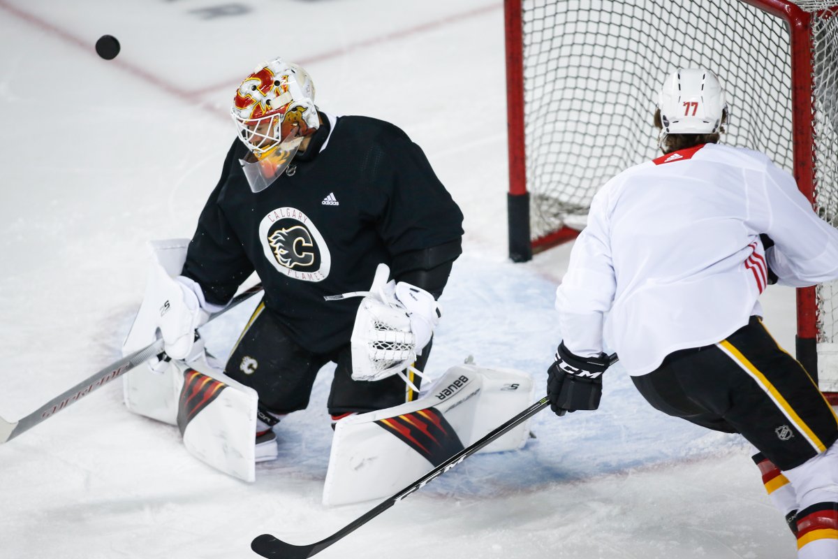 Calgary Flames goalie Cam Talbot deflects a shot from Mark Jankowski during practice in Calgary, Monday, July 13, 2020.