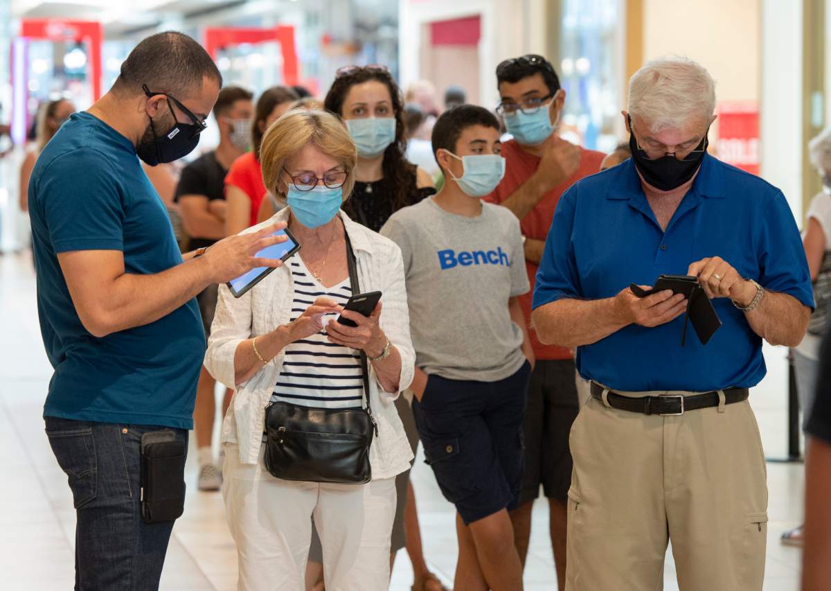 Shoppers wear masks as they line up at a mall on the third day of Quebec's mandatory mask order for all indoor public spaces 20, 2020 in Laval, Que. 