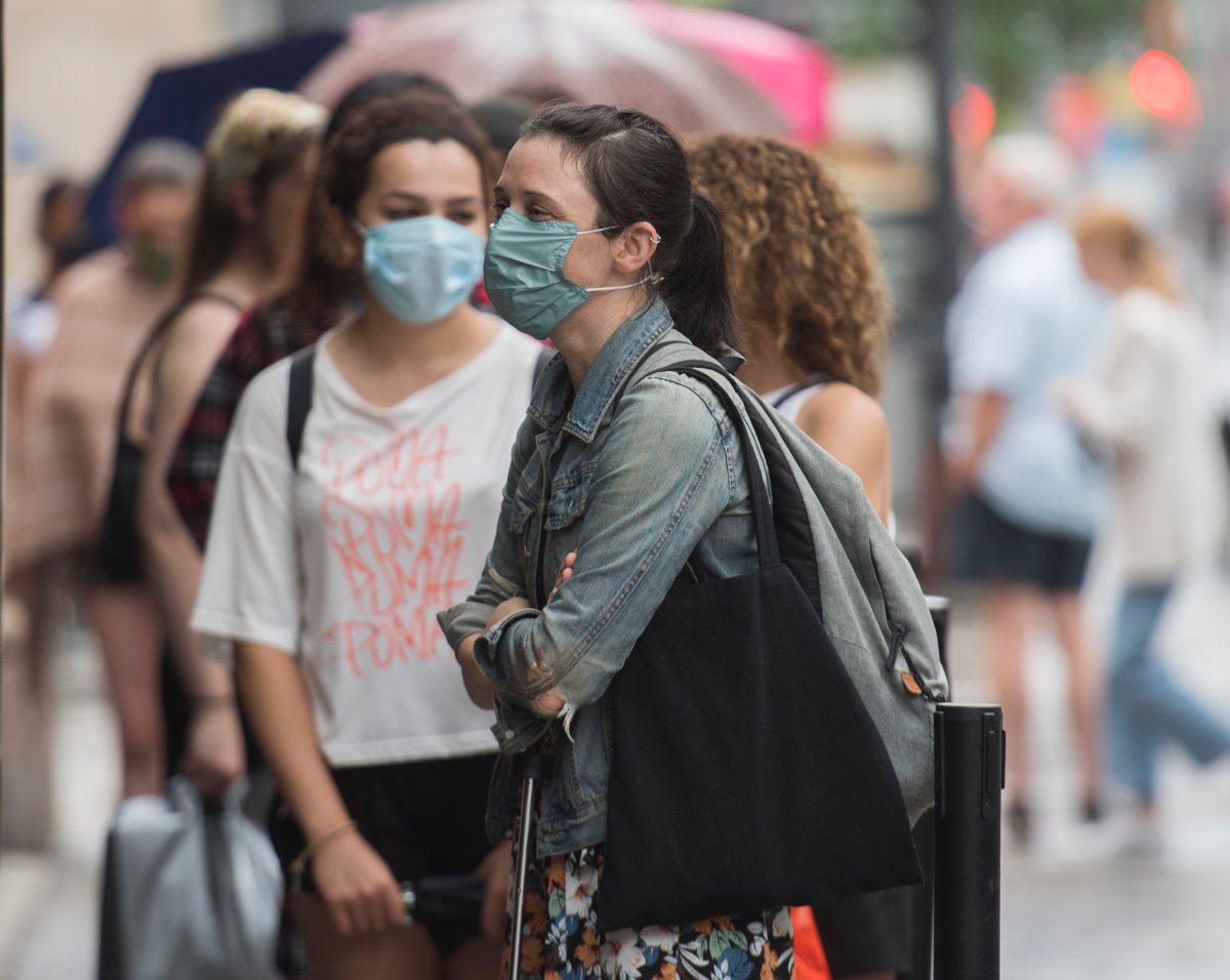 People wear face masks as they wait to enter a store in Montreal, Saturday, July 11, 2020, as the COVID-19 pandemic continues in Canada and around the world.  