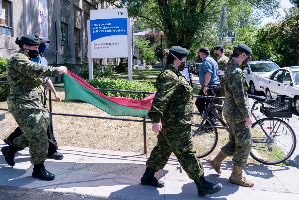 Soldiers walk away with the battalion flag following a ceremony marking the last day of military presence at the CHSLD Nazaire-Piche in Montreal, on June 17, 2020. 