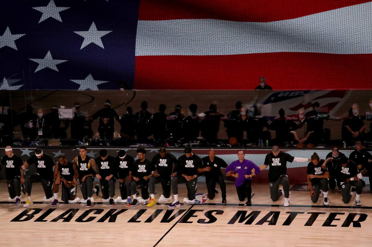 The Los Angeles Lakers and the Los Angeles Clippers wear Black Lives Matter shirts and kneel during the national anthem prior to an NBA basketball game Thursday, July 30, 2020, in Lake Buena Vista, Fla.