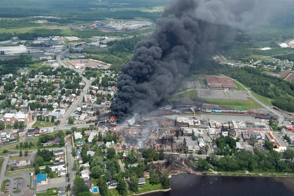 Smoke rises from railway cars that were carrying crude oil after derailing in downtown Lac-Mégantic, Que., Saturday, July 6, 2013. Lac-Megantic will mark the seventh anniversary of a tragic rail disaster that claimed 47 lives by inaugurating a long-planned memorial space. THE CANADIAN PRESS/Paul Chiasson.