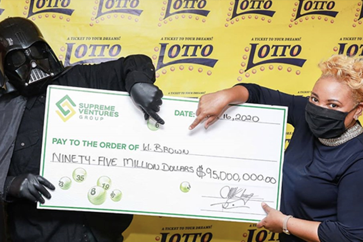 A man dressed as Darth Vader, left, claims his lottery winnings in Jamaica on July 16, 2020.