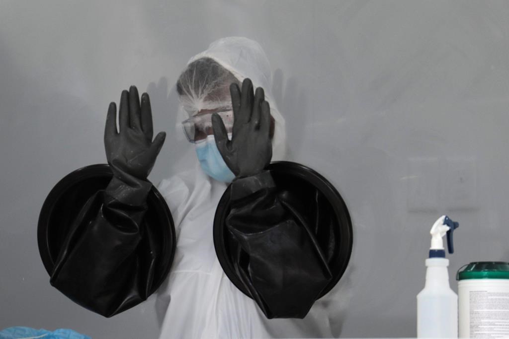 A health-care worker air dries her gloves after sanitizing her equipment while working at a walk-up COVID-19 testing site during the coronavirus pandemic, Friday, July 17, 2020, in Miami Beach, Fla.