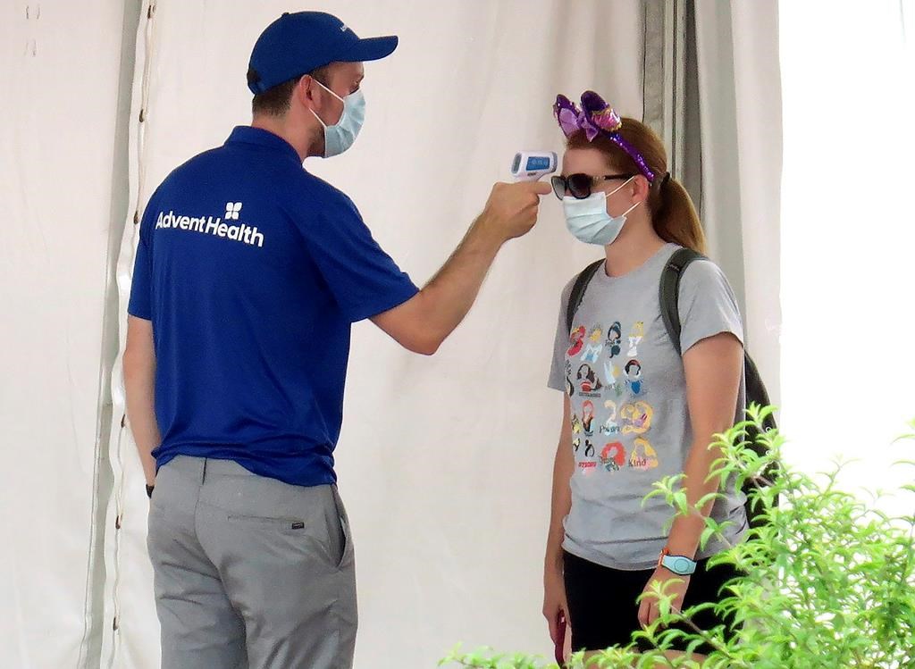 A guests gets her temperature taken before entering the official reopening day of the Magic Kingdom at Walt Disney World in Lake Buena Vista, Fla., Saturday, July 11, 2020. Disney reopened two Florida parks, the Magic Kingdom and Animal Kingdom, Saturday with limited capacity and safety protocols in place in response to the coronavirus pandemic. (Joe Burbank/Orlando Sentinel via AP).