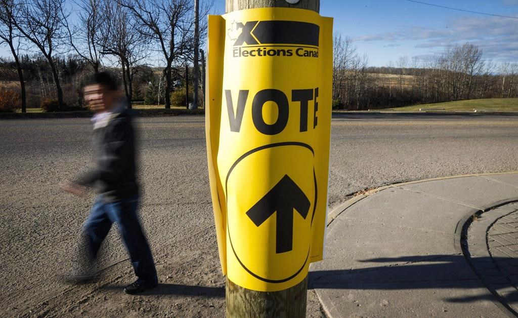 Canada's elections watchdog says a Quebec engineering firm illegally donated more than $46,000 to federal political entities over a period of seven years. A voter walks past a sign directing voters to a polling station for the Canadian federal election in Cremona, Alta., Monday, Oct. 19, 2015. THE CANADIAN PRESS/Jeff McIntosh.
