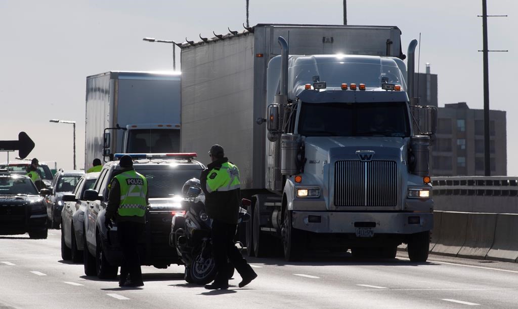 Trucks roll through a checkpoint as Quebec Provincial Police stop traffic heading into the province on an inter-provincial bridge, in Gatineau, Que., Thursday, April 2, 2020.