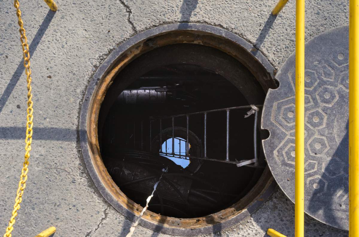 An open sewer grate is seen in a stock photo.