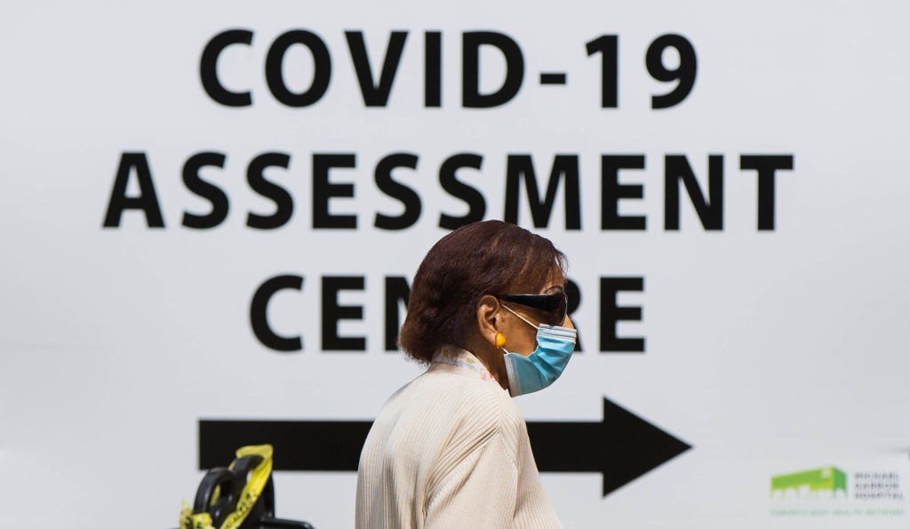 FILE - A woman wearing a face mask arrives at the COVID-19 assessment center of a hospital in Toronto, Canada, July 20, 2020.