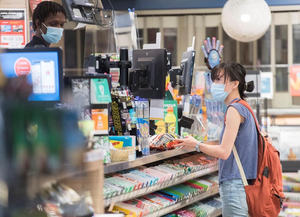 A woman wears a face mask at a convenience store in Montreal, Sunday, July 19, 2020, as the COVID-19 pandemic continues in Canada and around the world.