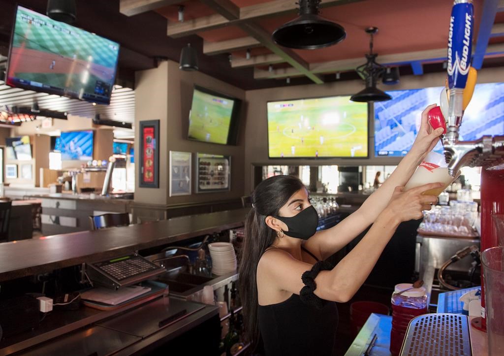 A server pulls a pint of beer at Station Sports bar in Montreal, Saturday, July 25, 2020, as the COVID-19 pandemic continues in Canada and around the world. THE CANADIAN PRESS/Graham Hughes.