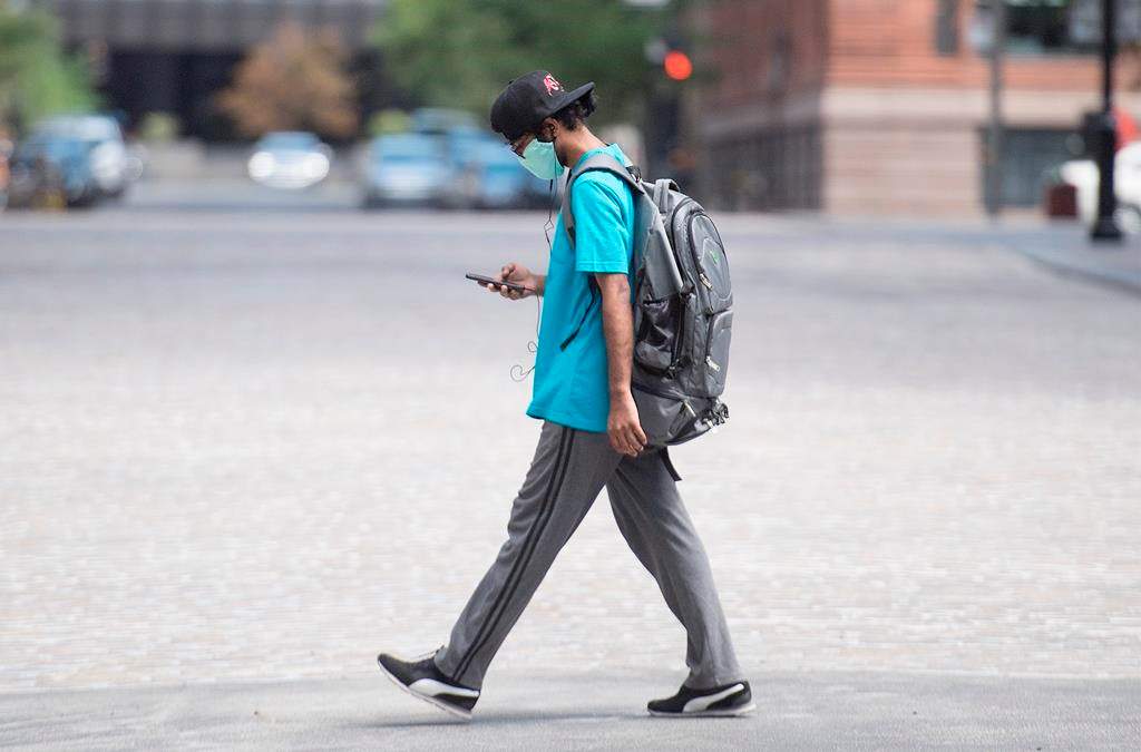 A man wears a face mask as he walks along a street in Montreal, Sunday, July 26, 2020, as the COVID-19 pandemic continues in Canada and around the world. THE CANADIAN PRESS/Graham Hughes.