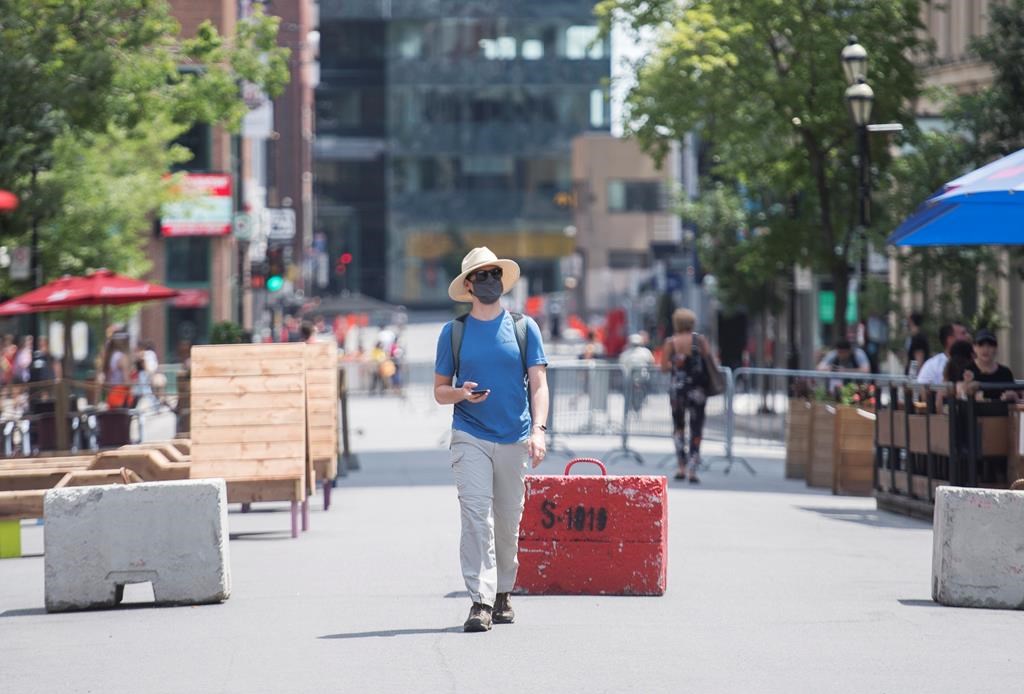 A man wears a face mask as he walks along a pedestrianised zone of Crescent Street in Montreal, Saturday, July 25, 2020, as the COVID-19 pandemic continues in Canada and around the world. THE CANADIAN PRESS/Graham Hughes.