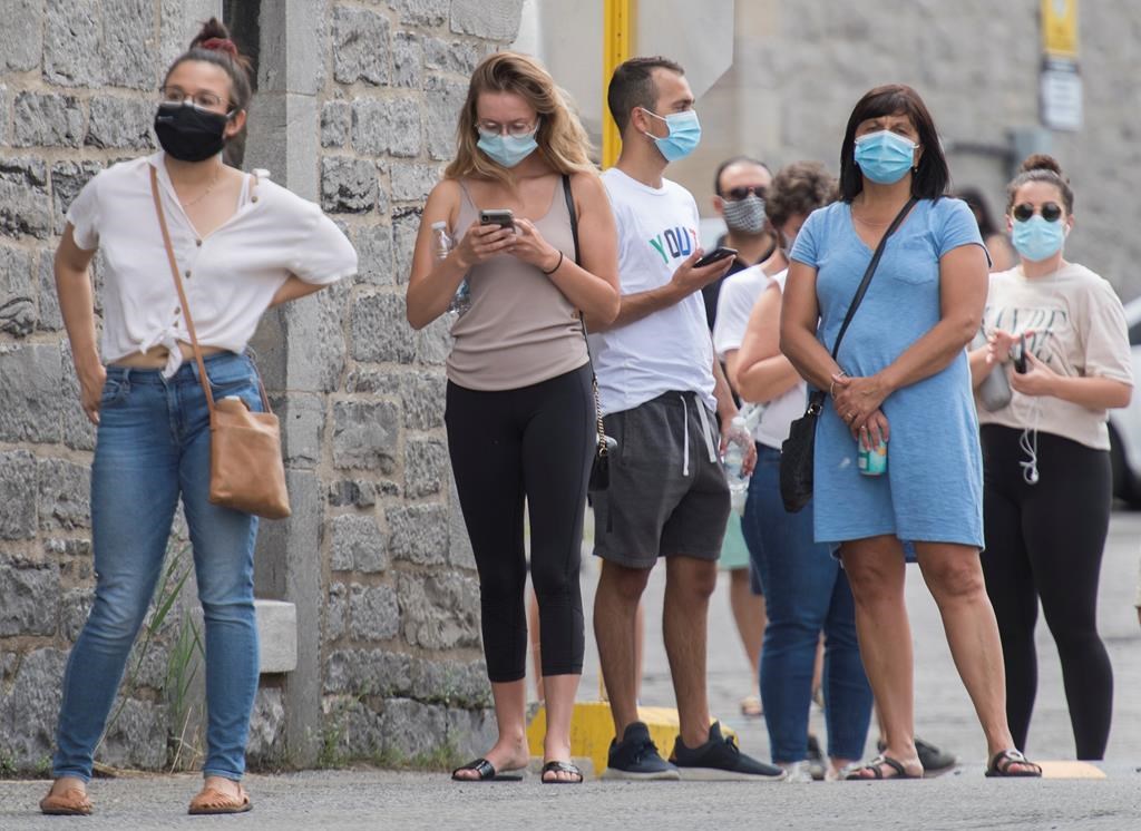People wait to be tested for COVID-19 at a testing clinic in Montreal, Sunday, July 12, 2020, as the COVID-19 pandemic continues in Canada and around the world. Quebec plans to make masks mandatory in all public indoor spaces across the province this week, several media outlets are reporting. THE CANADIAN PRESS/Graham Hughes.
