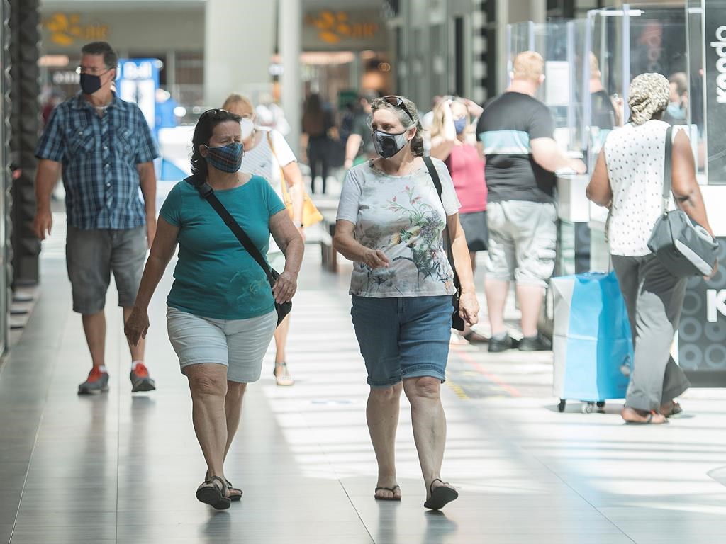 People wear face masks as they walk through a shopping mall in Montreal, Saturday, July 18, 2020, as the COVID-19 pandemic continues in Canada and around the world. The wearing of masks or protective face coverings is mandatory in Quebec as of today. THE CANADIAN PRESS/Graham Hughes.