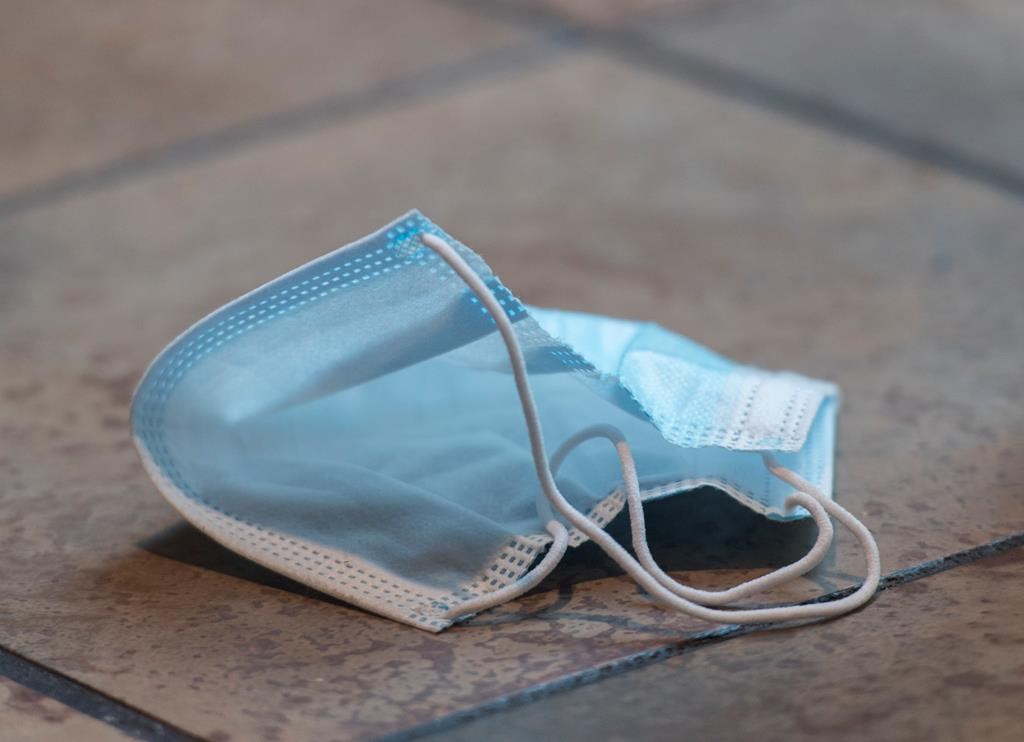A discarded face mask is shown on the floor of a food court in a shopping mall. 