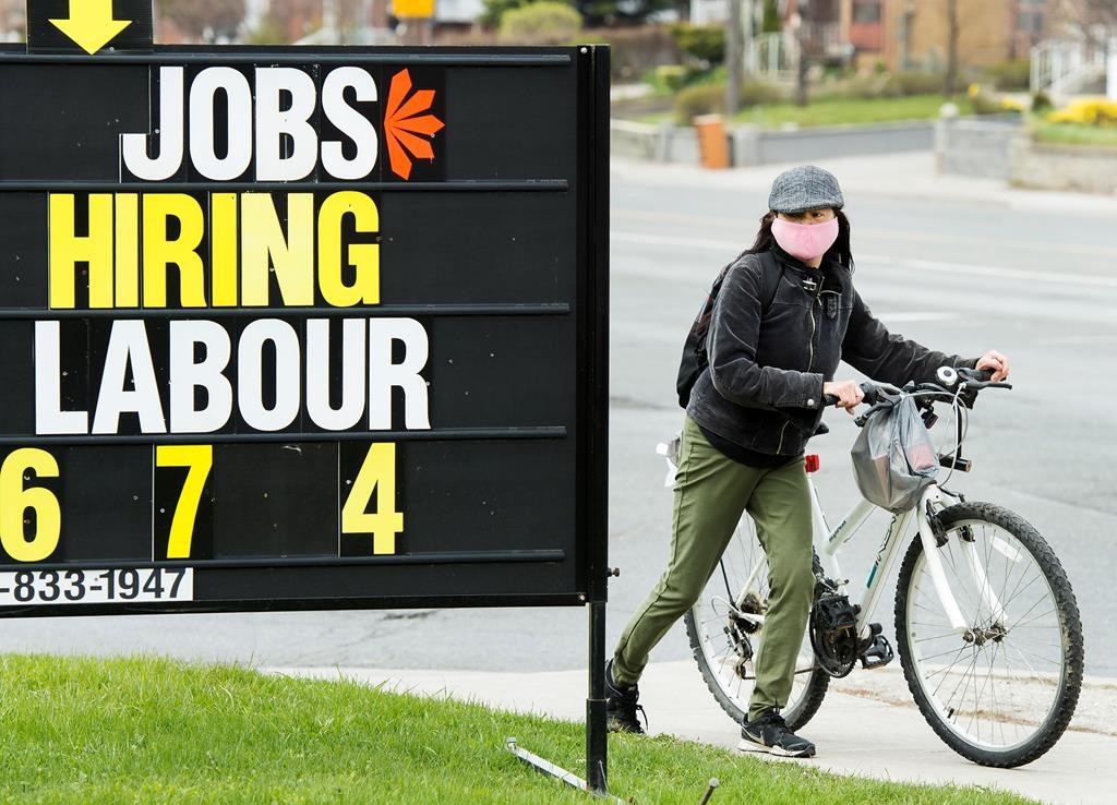 A woman checks out a jobs advertisement sign during the COVID-19 pandemic in Toronto on April 29, 2020.
