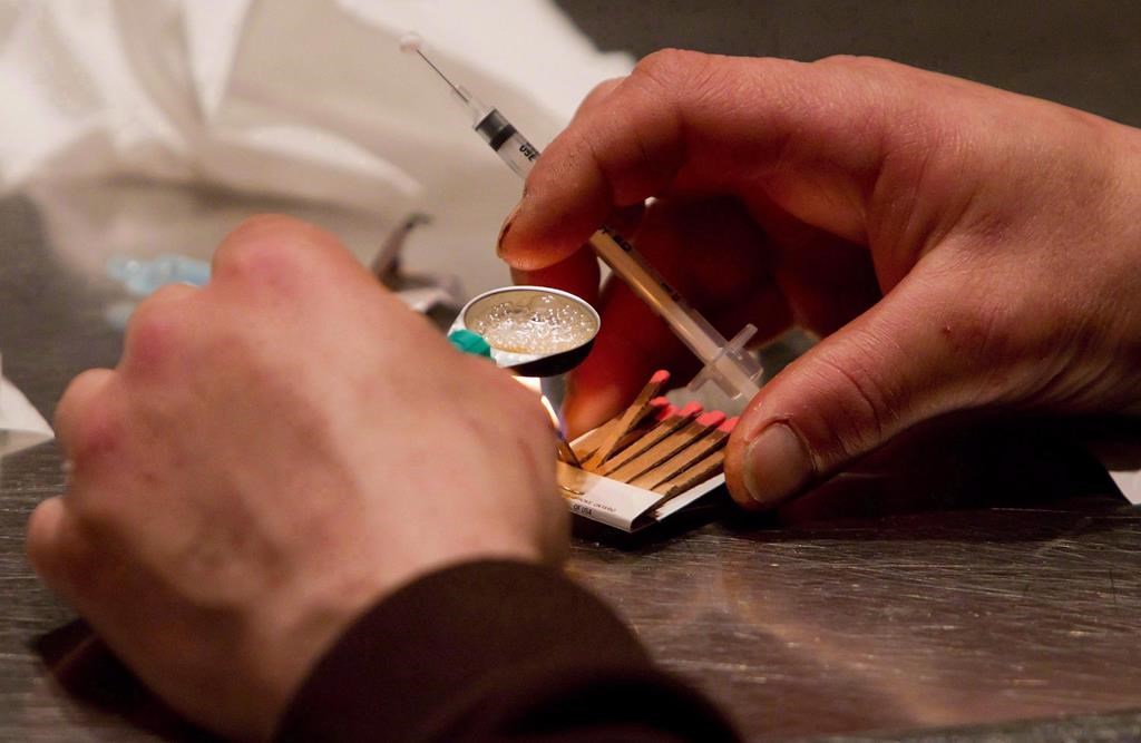 A man prepares heroin he bought on the street to be injected at the Insite safe injection clinic in Vancouver, B.C., on Wednesday May 11, 2011.