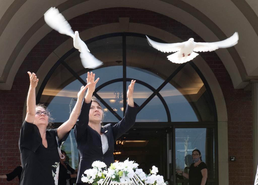 Josee Masson, left, and Marie-Eve Garneau release two doves at end of the funerals of Romy and Norah Carpentier, at the funeral home in Levis, Que., Monday, July 20, 2020.