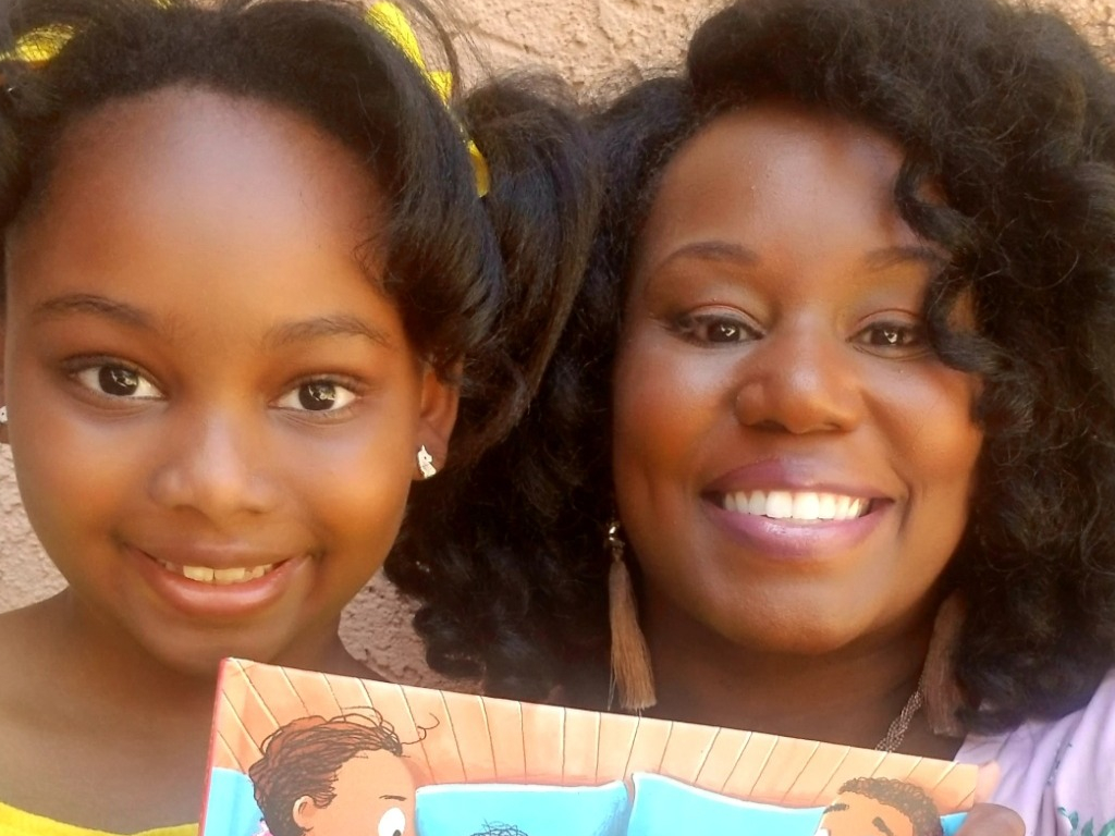 Madison Wilson, 7, and her mom hold up her favourite book, ‘The Big Bed’ by Bunmi Laditan.