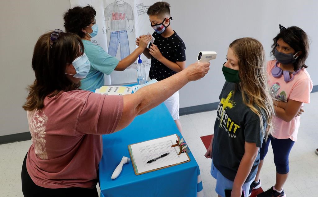 In this Tuesday, July 14, 2020 file photo, teachers check students before a summer STEM camp at Wylie High School in Wylie, Texas.