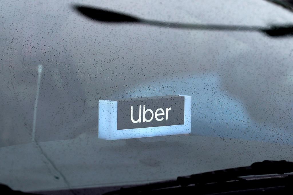 FILE - In this May 15, 2020 file photo, an Uber sign is displayed inside a car in Chicago. Uber finally got its food delivery company, acquiring Postmates in a $2.65 billion all-stock deal, the ride-hailing giant confirmed Monday, July 6.