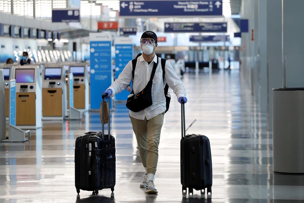 FILE - In this June 16, 2020 file photo, a traveler wears a mask and protective goggles as he walks through Terminal 3 at O'Hare International Airport in Chicago. United Airlines says its face mask requirement now extends to ticket counters and airport lounges. United said Wednesday, July 22 that it might ban violators from flying on its planes. United and all other major U.S. airlines already require passengers to wear masks during flights. (AP Photo/Nam Y. Huh, File).