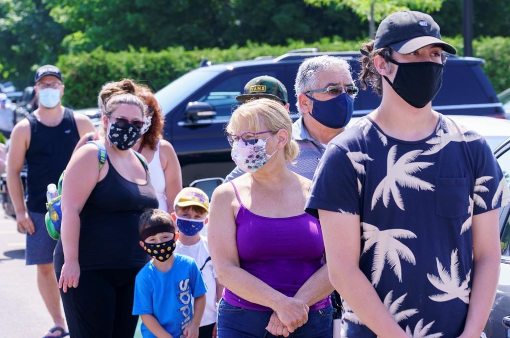 People line up to enter a mobile COVID-19 test clinic in Mercier, Que., Thursday, July 9, 2020. A small community south of Montreal is making mask-wearing mandatory beginning today inside all commercial businesses following a COVID-19 outbreak authorities say is tied to a house party.THE CANADIAN PRESS/Paul Chiasson.