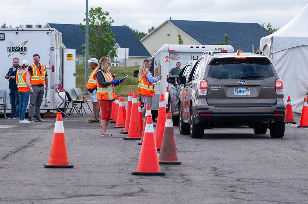 Volunteers examine the documents of motorists who just came off the Confederation Bridge in Borden-Carleton, P.E.I., Friday, July 3, 2020. s.