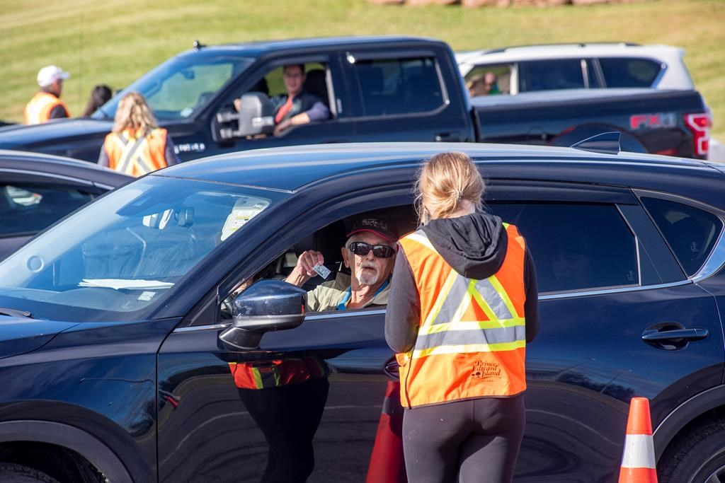 A motorist shows his identification to a provincial worker at the Confederation Bridge in Borden-Carleton, P.E.I., Friday, July 3, 2020. Prince Edward Island's chief medical officer of health is strongly urging people to wear non-medical face masks indoors but so far isn't recommending they be mandatory.