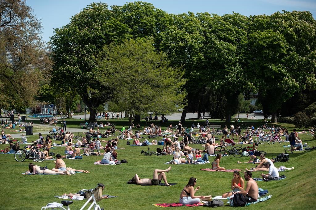People sit and lie in the sun at Kitsilano Beach Park in Vancouver, on Saturday, May 9, 2020.