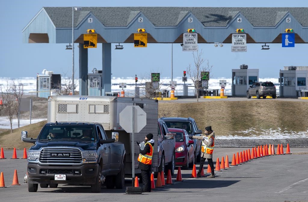 Provincial health department workers stop traffic that has crossed the Confederation Bridge in Borden-Carleton, P.E.I. on Sunday, March 22, 2020. Atlantic Canadian provinces will lift travel restrictions within the region starting tomorrow, with some identification from visitors required. THE CANADIAN PRESS/Andrew Vaughan.