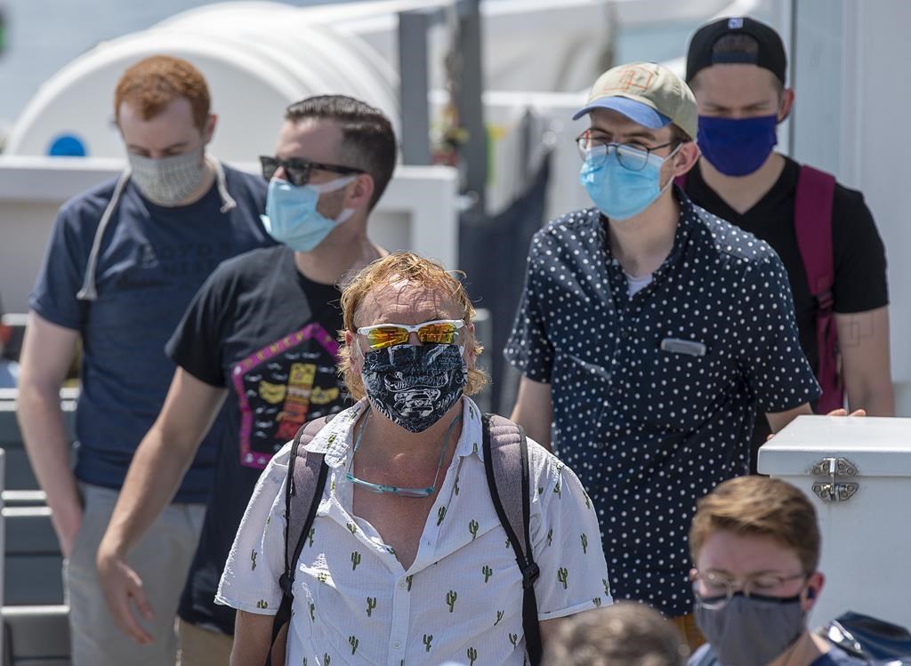 Passengers wear face masks on a Halifax Transit ferry as it arrives in Dartmouth, N.S. on Friday, July 24, 2020, the first day they have been mandatory on public transit. Masks will become mandatory in most indoor public places in Nova Scotia on Friday and the province's health minister says it will be up to the public to carry out its responsibility to wear them. THE CANADIAN PRESS/Andrew Vaughan.