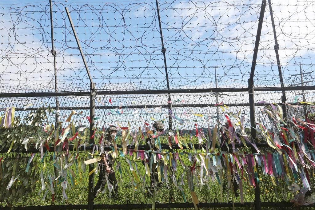 South Korean army soldiers wearing face masks to help protect against the spread of the new coronavirus pass by a wire fence decorated with ribbons written with messages wishing for the reunification of the two Koreas at the Imjingak Pavilion in Paju, near the border with North Korea, Sunday, July 26, 2020. North Korean leader Kim Jong Un placed the city of Kaesong near the border with South Korea under total lockdown after a person was found with suspected COVID-19 symptoms, saying he believes "the vicious virus" may have entered the country, state media reported Sunday.