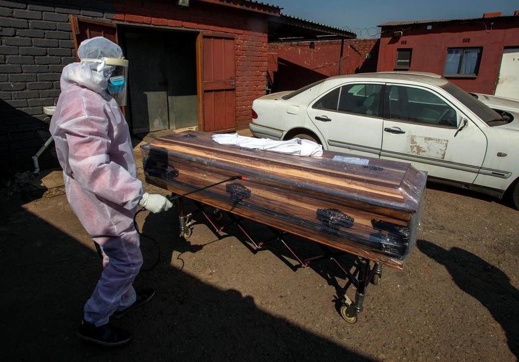 A funeral home worker in a protective suit disinfects a coffin carrying a woman who died from COVID-19 as they prepare for a funeral in Katlehong, near Johannesburg, South Africa, Tuesday, July 21, 2020. (AP Photo/Themba Hadebe)