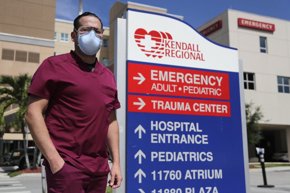 Rublas Ruiz poses for a photograph outside of Kendall Regional Medical Hospital where he works as a nurse in the hospital’s intensive care unit, Tuesday, Aug. 11, 2020, in Miami. While other nurses rotate in and out of the COVID-19 ICU unit to limit their exposure to the deadly virus, Ruiz has asked to stay permanently.