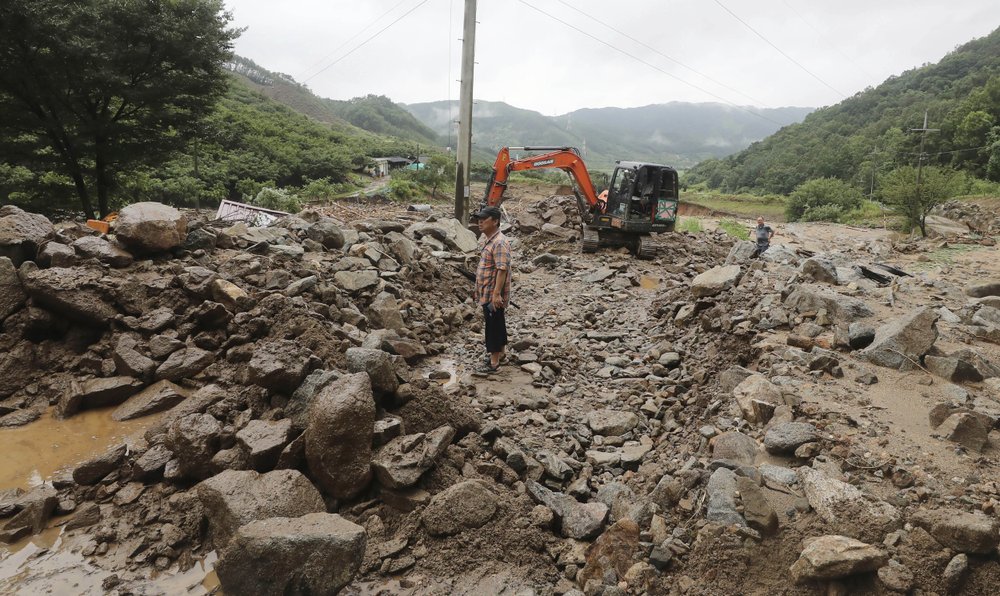A man stands on road covered with mud and rocks after heavy rains in Chungju, South Korea, Sunday, Aug. 2, 2020. South Korean Meteorological Administration issued a warning of heavy rain for Seoul and central area. 
