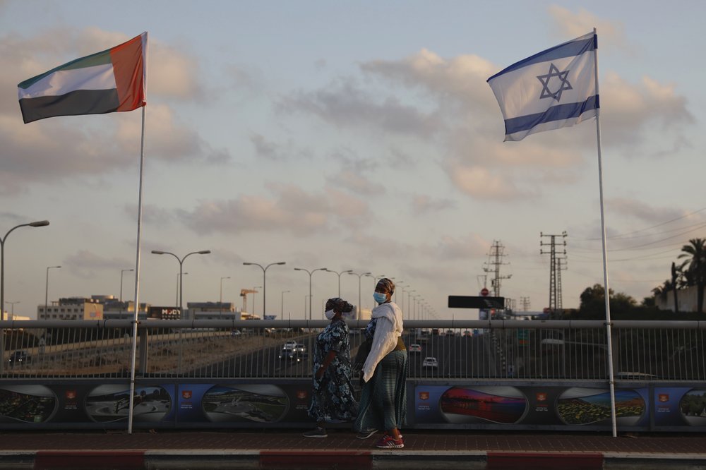 Women wearing face masks against the coronavirus walk past United Arab Emirates and Israeli flags at the Peace Bridge in Netanya, Israel, Sunday, Aug. 16, 2020. The UAE flag was displayed to celebrate last week's announcement that Israel and the United Arab Emirates have agreed to establish full diplomatic relations.
