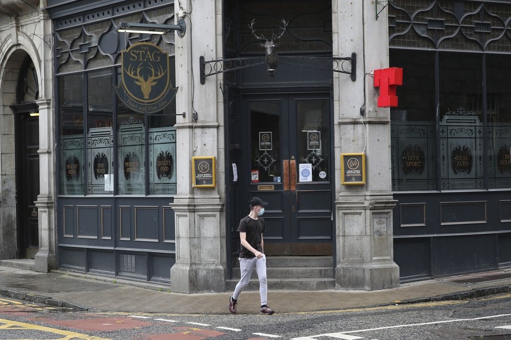 A man walks past the closed Stag pub, after bars, cafes and restaurants were ordered to close as lockdown restrictions were reimposed due to a coronavirus cluster in the area, in Aberdeen, Scotland, Wednesday, Aug. 5, 2020. A five-mile travel rule has been put in place and residents are being told not to enter each other's houses as First Minister Nicola Sturgeon said over 50 cases have now been reported. 
