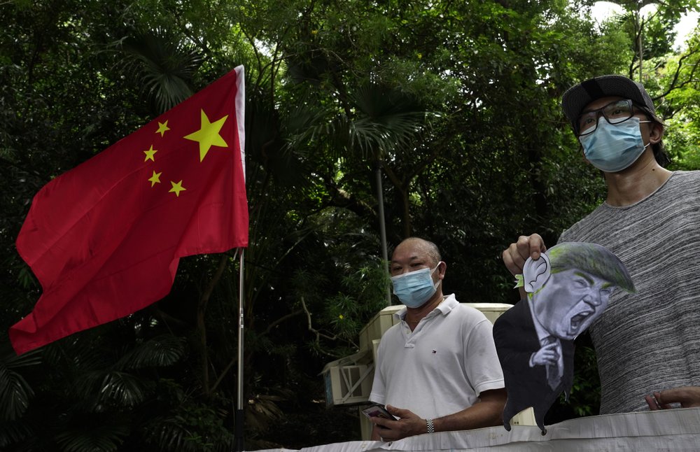 Pro-China supporters displays a picture of U.S. President Donald Trump during a protest against the U.S. sanctions outside the U.S. Consulate in Hong Kong Saturday, Aug. 8, 2020. The U.S. on Friday imposed sanctions on Hong Kong officials, including the pro-China leader of the government, accusing them of cooperating with Beijing's effort to undermine autonomy and crack down on freedom in the former British colony. 