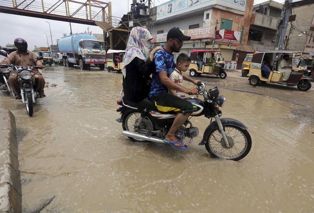 Motorcyclists drive through a road flooded by heavy rainfall in Karachi, Pakistan, Sunday, Aug. 9, 2020. Three days of heavy monsoon rains triggering flash floods killed at least dozens people in various parts of Pakistan, as troops with boats rushed to a flood-affected district in the country's southern Sindh province Sunday to evacuate people to safer places.