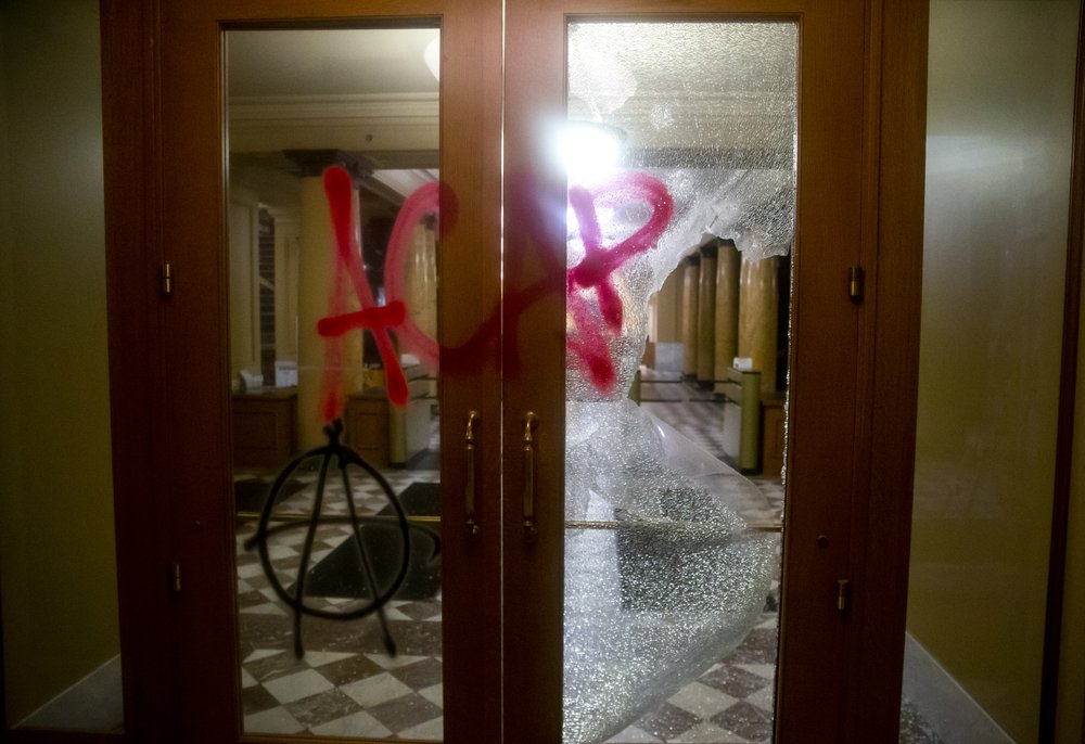 Graffiti is sprayed on a damaged door at City Hall in Portland Ore., on Tuesday, Aug. 25, 2020. Officials say protesters in Portland smashed windows at City Hall in a demonstration that started Tuesday night and stretched into Wednesday morning. 