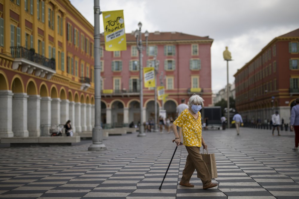 A woman wearing a mask to protect against the coronavirus walks through the Place Massena in Nice, southern France, Friday, Aug 28, 2020. The Tour de France sets off Saturday Aug. 29, shrouded in uncertainty in the face of the coronavirus pandemic and mounting infections in France. 
