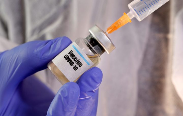 FILE PHOTO: A woman holds a small bottle labeled with a "Vaccine COVID-19" sticker and a medical syringe in this illustration taken April 10, 2020. 