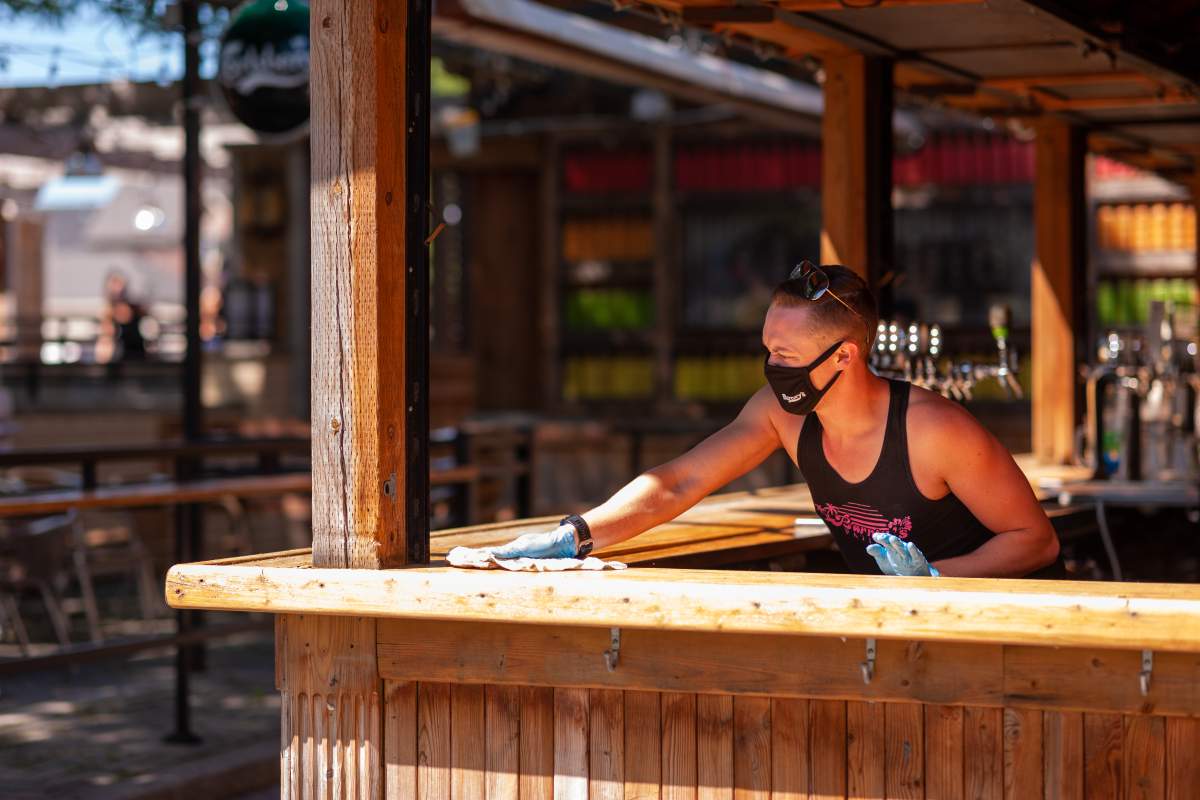 A worker at Barney's patio on Richmond Street in London, Ont., cleans the bar on June 12, 2020. 