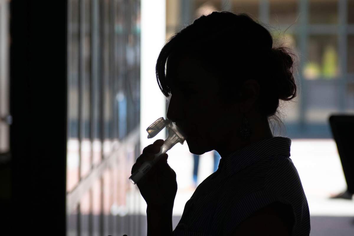 In this June 23, 2020 photo provided by UC Berkeley, a student provides saliva for an experimental COVID-19 coronavirus test for asymptomatic people. A group of Israeli researchers is also working on a saliva detection test. 
