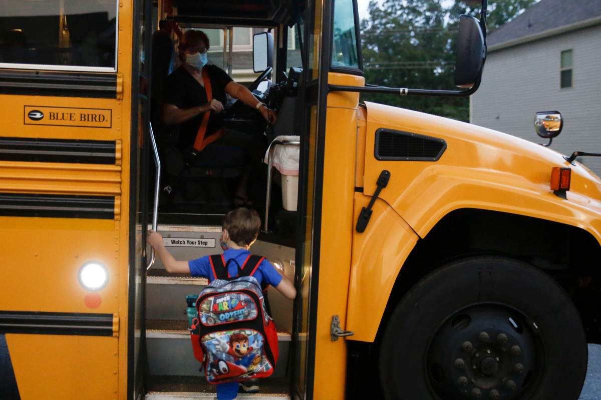 Paul Adamus, 7, climbs the stairs of a bus before the fist day of school on Monday, Aug. 3, 2020, in Dallas, Ga.